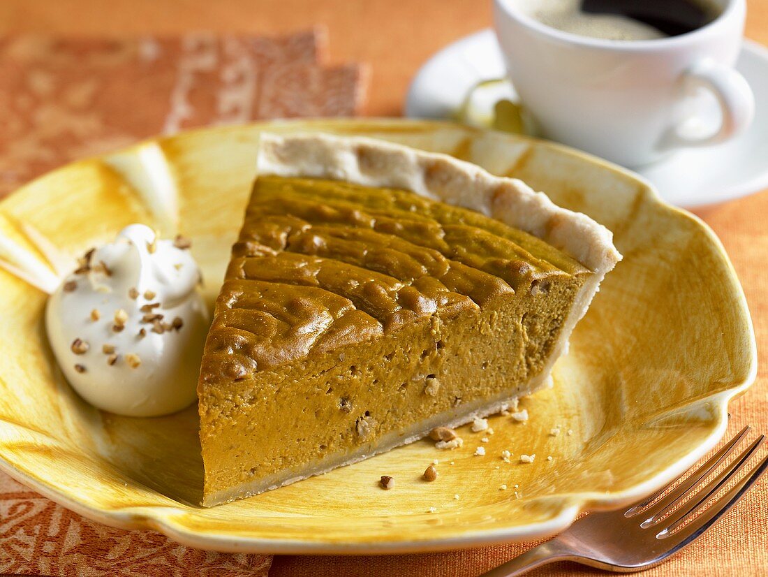 Ein Stück Kürbiskuchen mit Creme fraiche und eine Tasse Kaffee