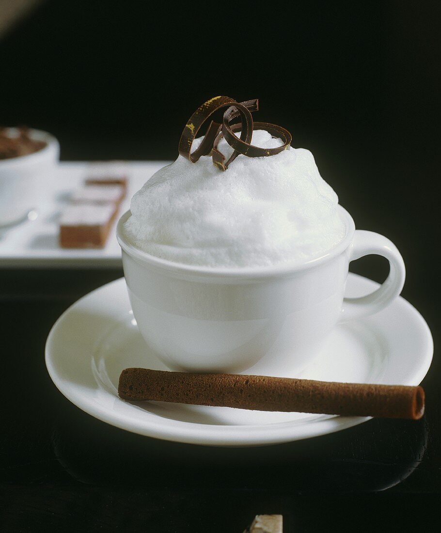 Tasse Kakao mit Milchschaum und Hippenröllchen