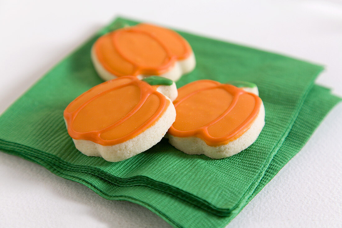 Three pumpkin biscuits for Halloween on a green napkin