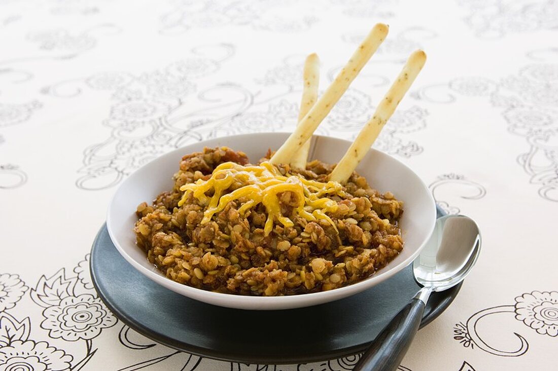 Bowl of Lentil Chili with Melted Cheese and Bread Sticks