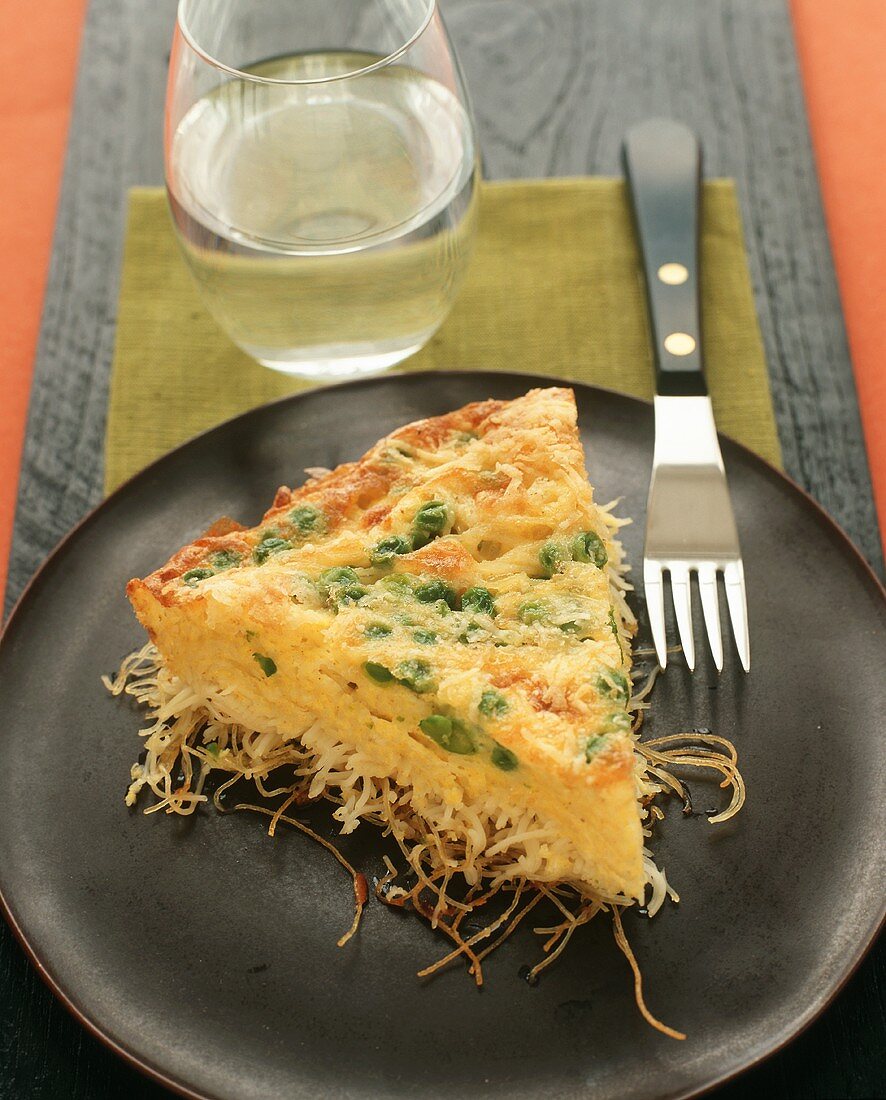 Slice of Baked Spaghetti Pie with Peas; Glass of Water
