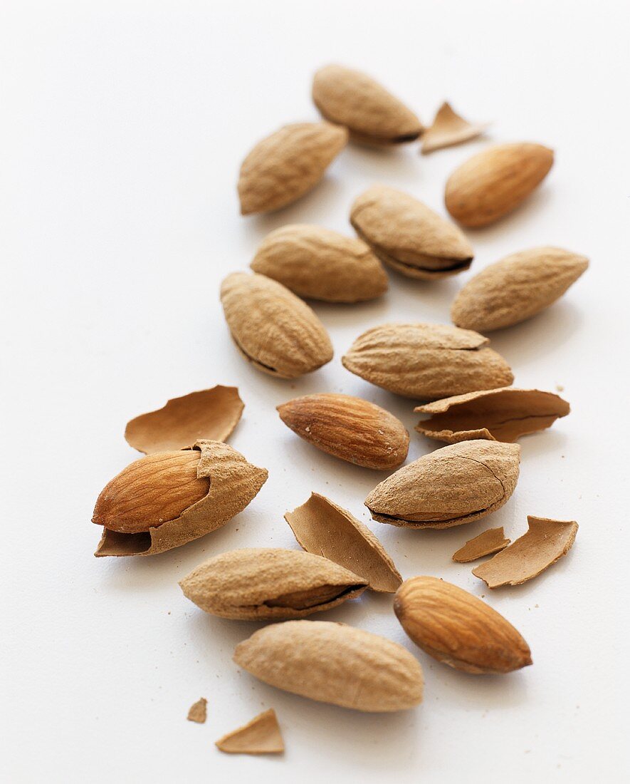 Many Whole and Shelled Almonds on a White Background