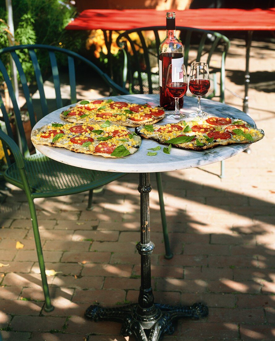 Outdoor Table with Corn, Tomato and Basil Pizza; Red Wine