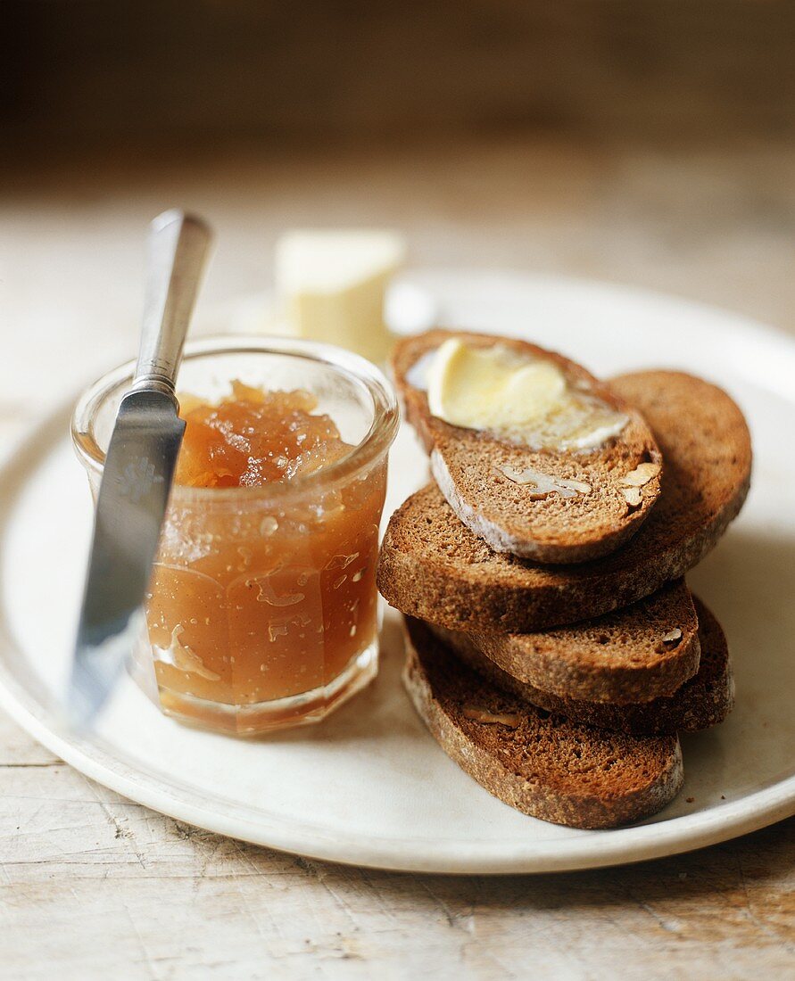 Stack of Walnut Toast; Top Slice with Butter; Jar of Jam with Knife