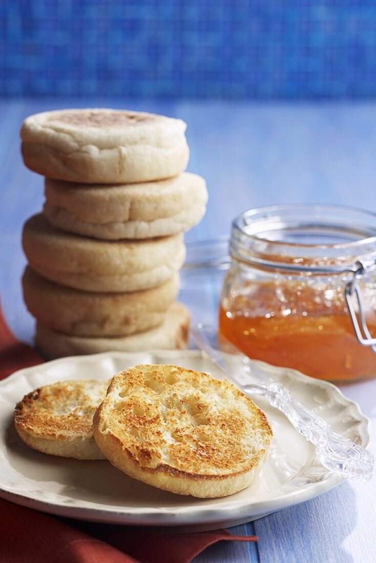 A Stack of English Muffins, One Toasted, and a Jar of Marmalade