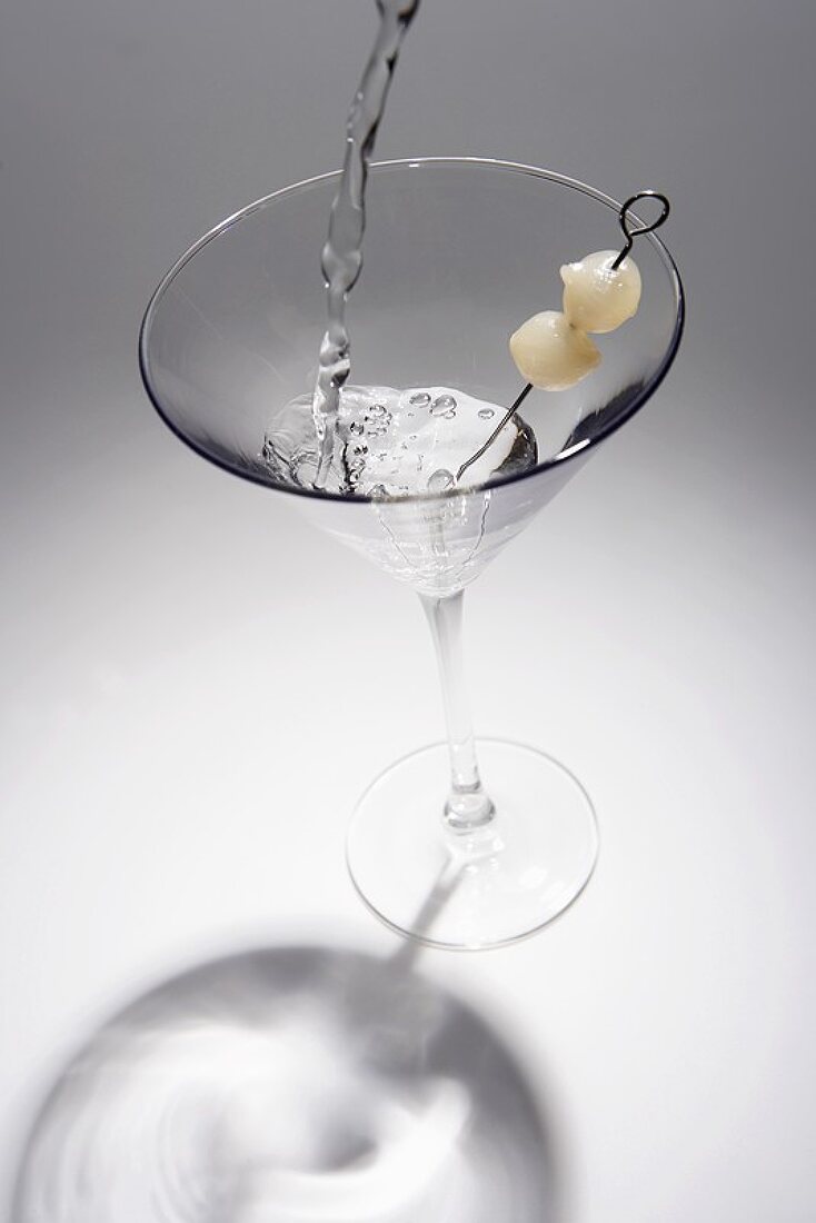 Gibson-Martini in ein Glas mit Perlzwiebeln einschenken