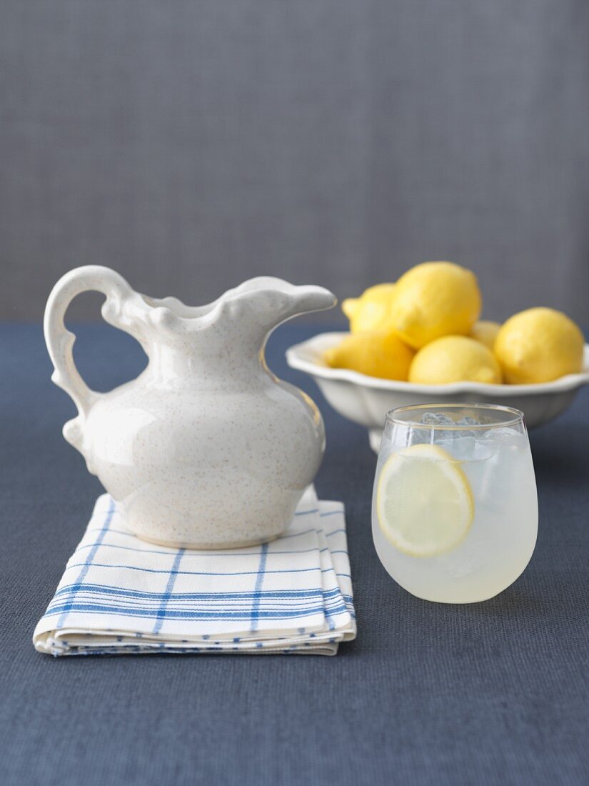 Ein Glas Zitronenlimonade mit Krug und Zitronen