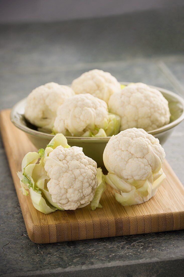 Heads of Baby Cauliflower in a Metal Bowl on Cutting Board