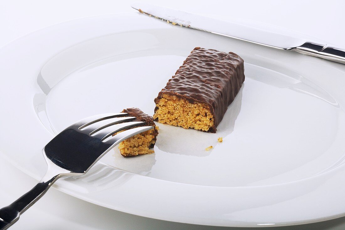 Chocolate Covered Protein Bar Cut on a Plate; Fork and Knife