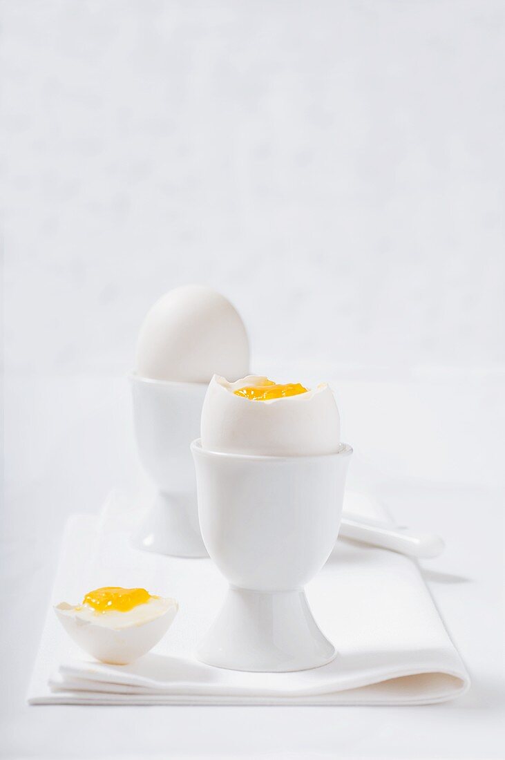 Weichgekochte Eier im Eierbecher, eines geköpft