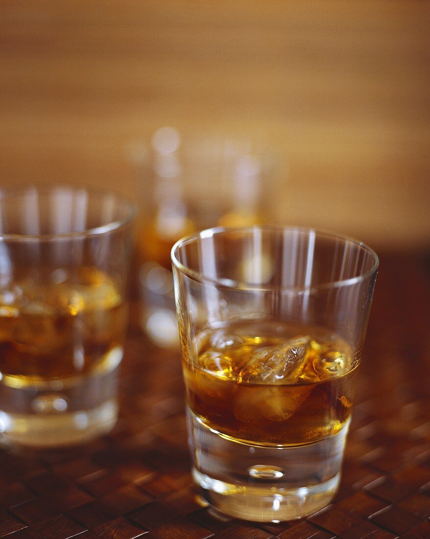 Brauner Rum mit Eiswürfeln in drei Gläsern