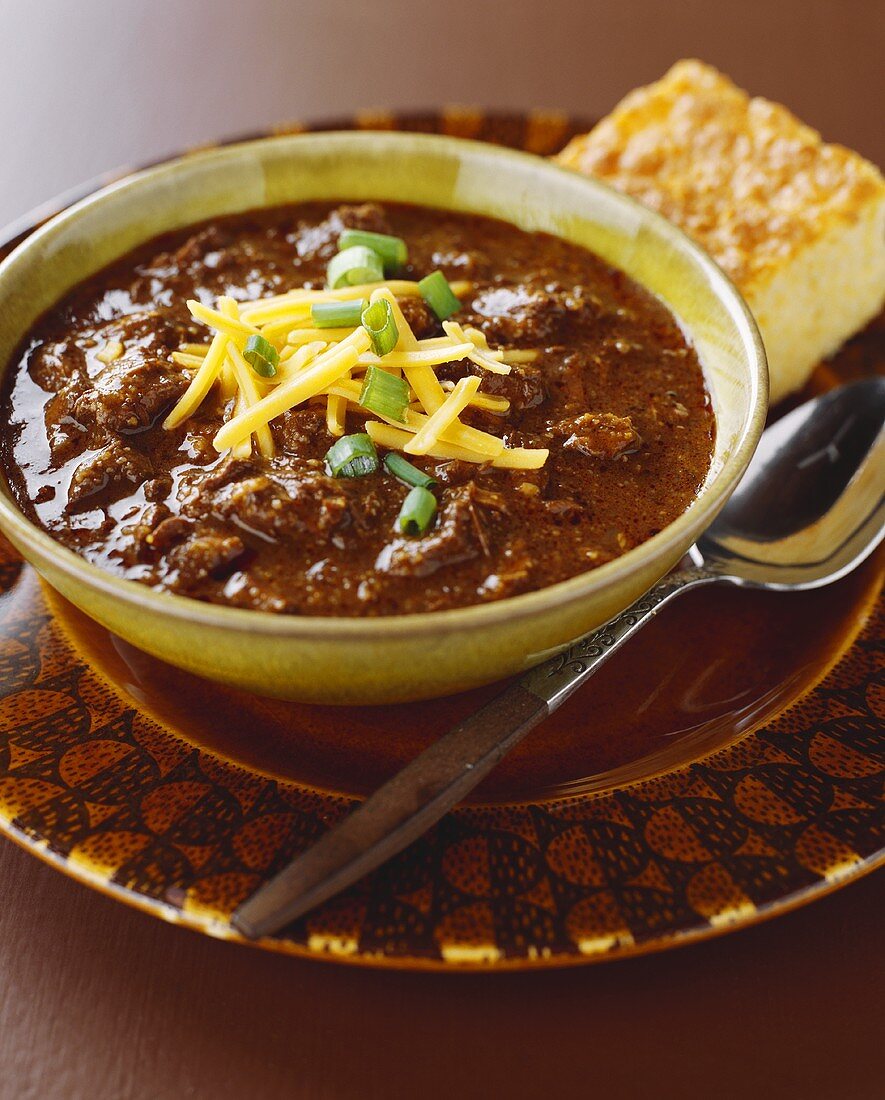 Bowl of Chili with Shredded Cheese and Corn Bread