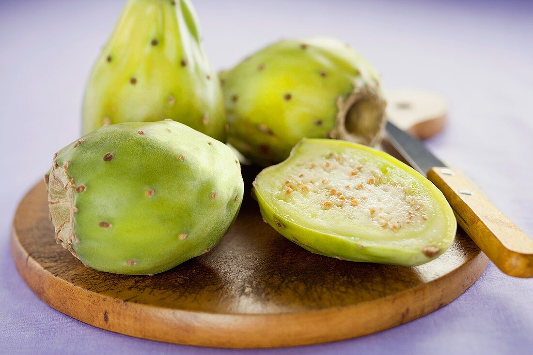 Half a Prickly Pear with Whole Prickly Pears on Cutting Board