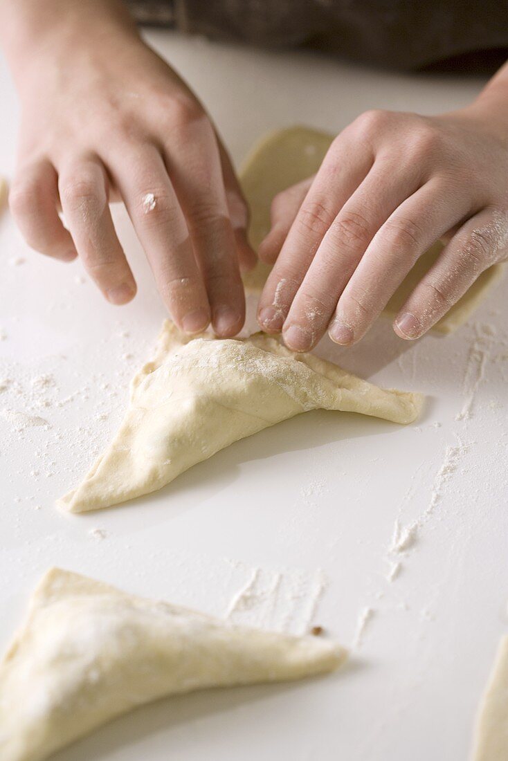 Child Sealing Edges of Meat Filled Pastries