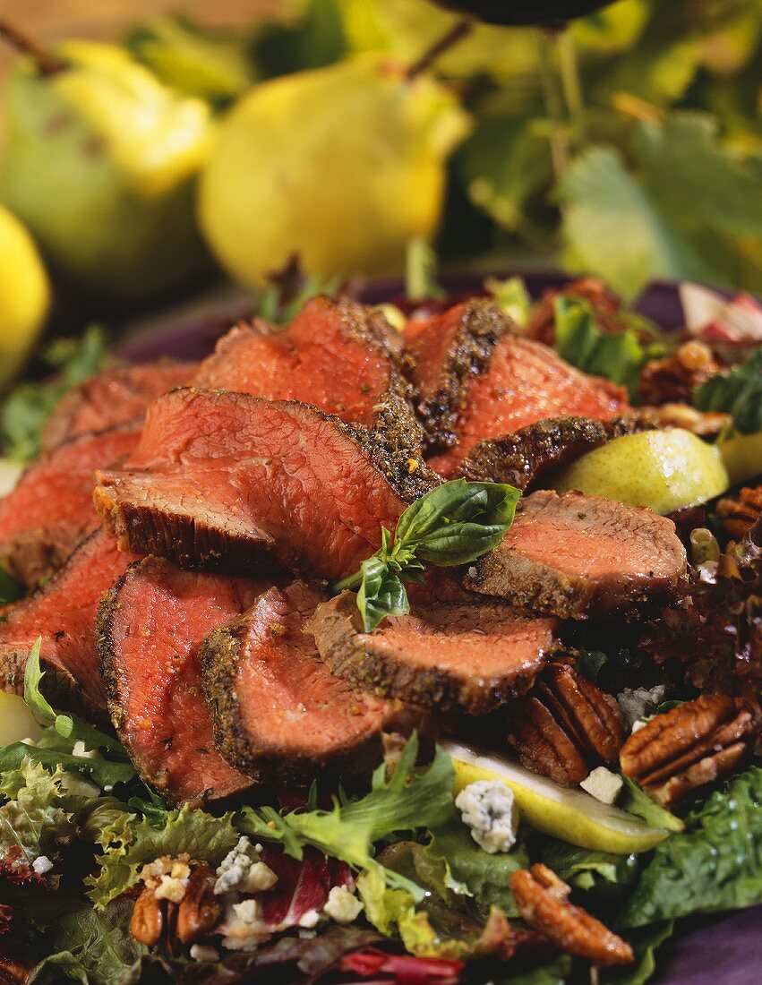 Steak-Scheiben auf Blattsalat mit Pekannüssen und Birnen