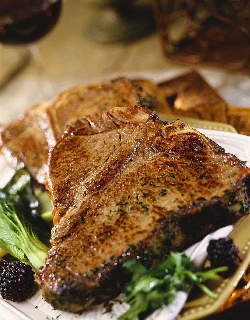 Zwei gegrillte T-Bone-Steaks mit Brombeeren