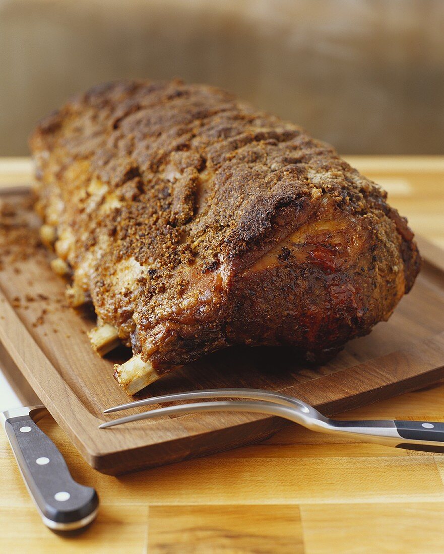 Gebratene Rinderhochrippe (Prime-Rib) auf einem Schneidebrett