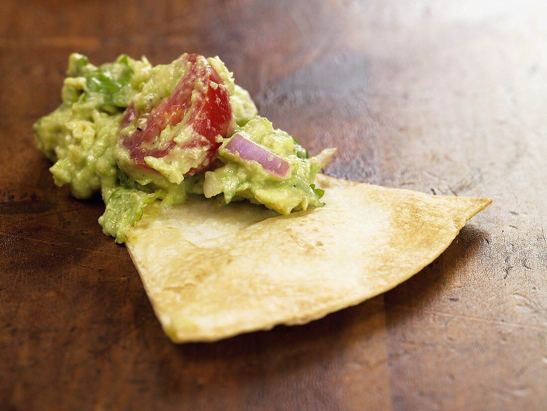 Tortilla Chip mit Guacamole auf Holzuntergrund