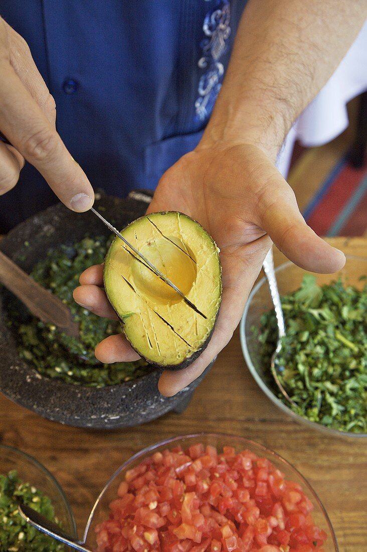 Mann bereitet Guacamole zu, Avocado schneiden