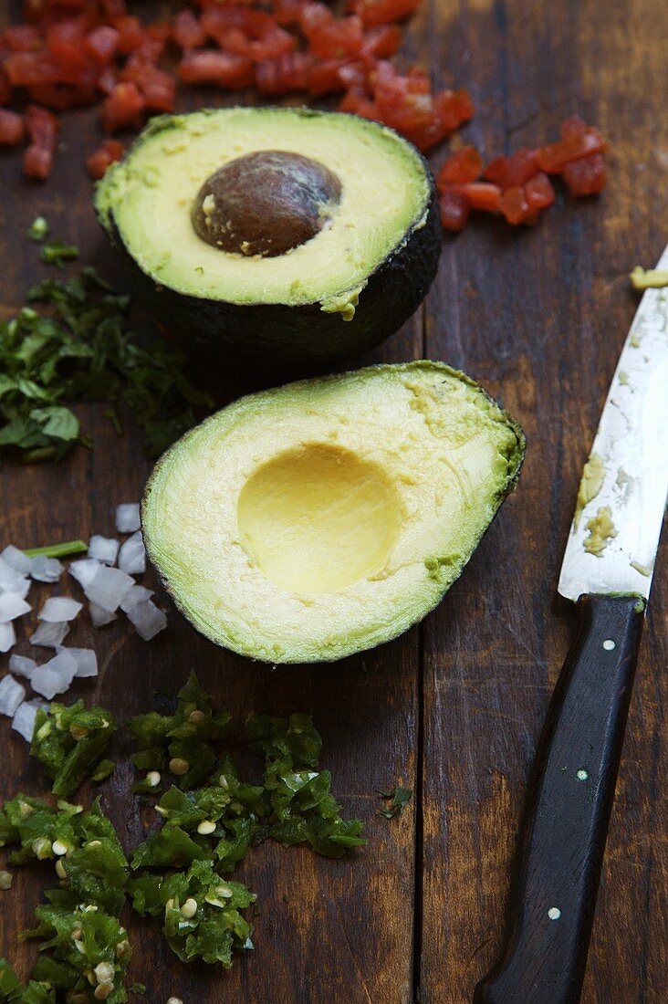 Zutaten für Guacamole auf Holzuntergrund mit einem Messer