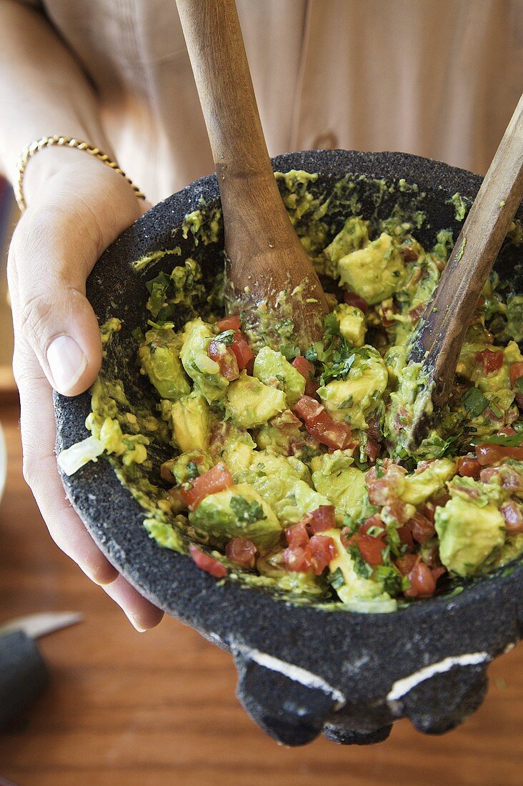 Mann hält Guacamole in einem Mörser in der Hand