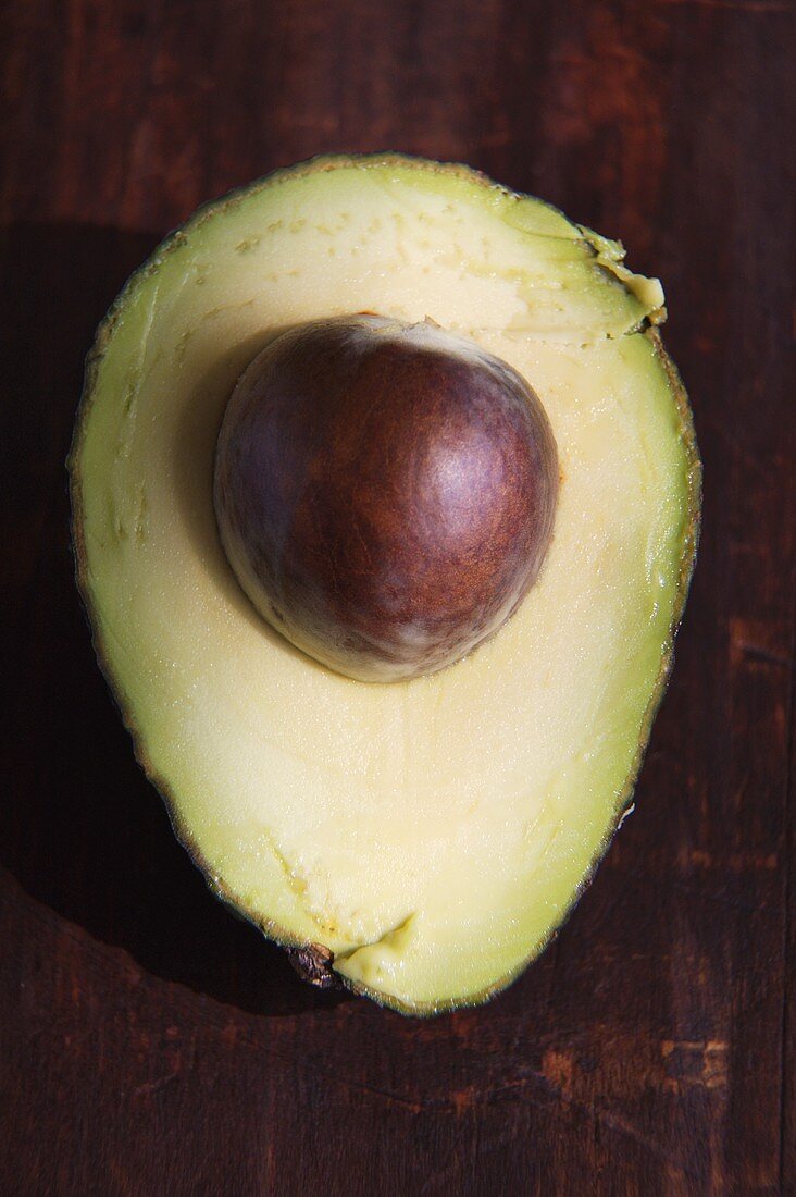 Half an Avocado with Pit on Wood