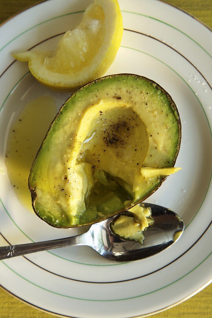 Avocado-Hälfte mit Vinaigrette und schwarzem Pfeffer