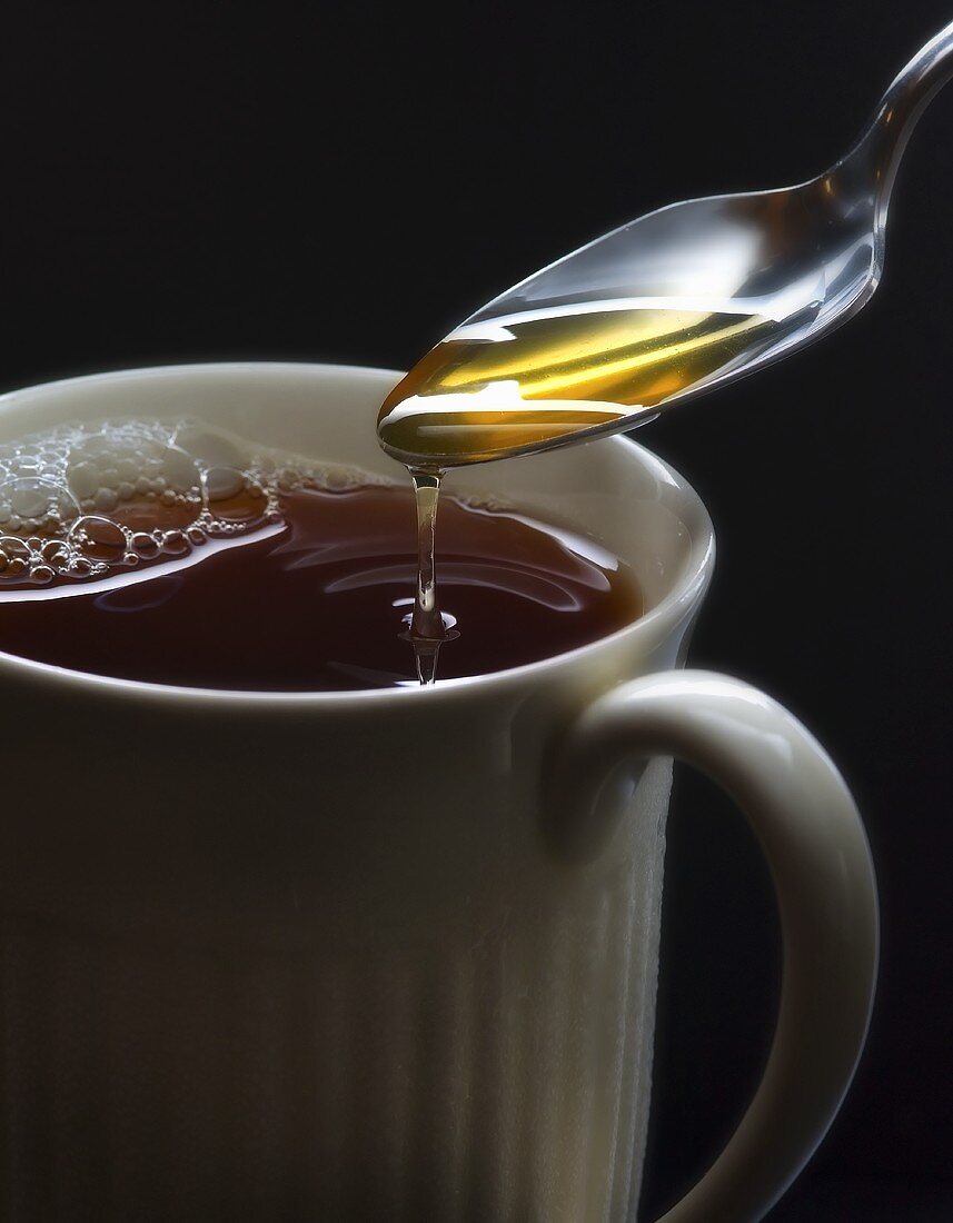 Honig in eine Tasse Tee fliessen lassen