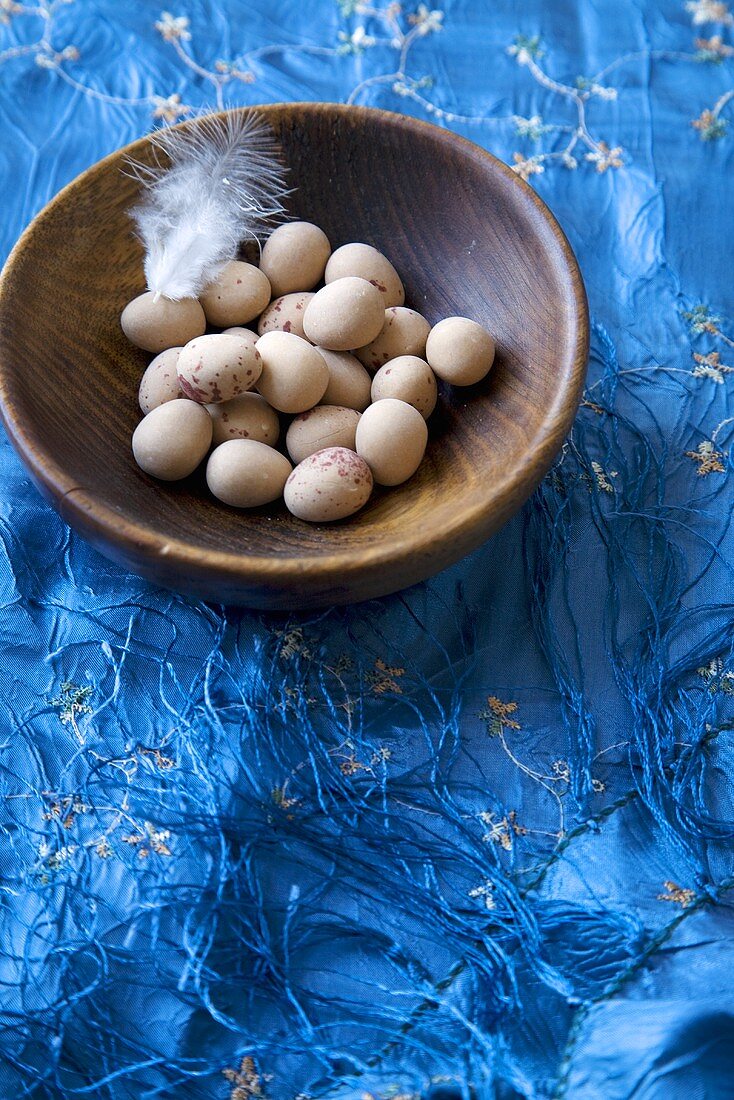 Zucker-Ostereier in einem Holzschälchen auf blauem Tuch