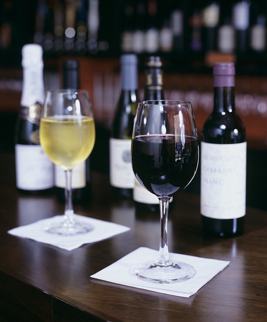 Glasses of Red and White Wine with Bottles on Bar