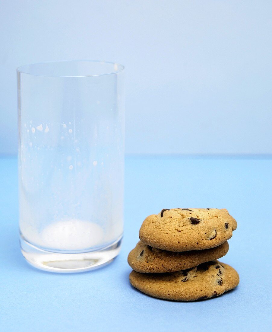 Drei Chocolate Chip Cookies mit ausgetrunkenem Glas Milch
