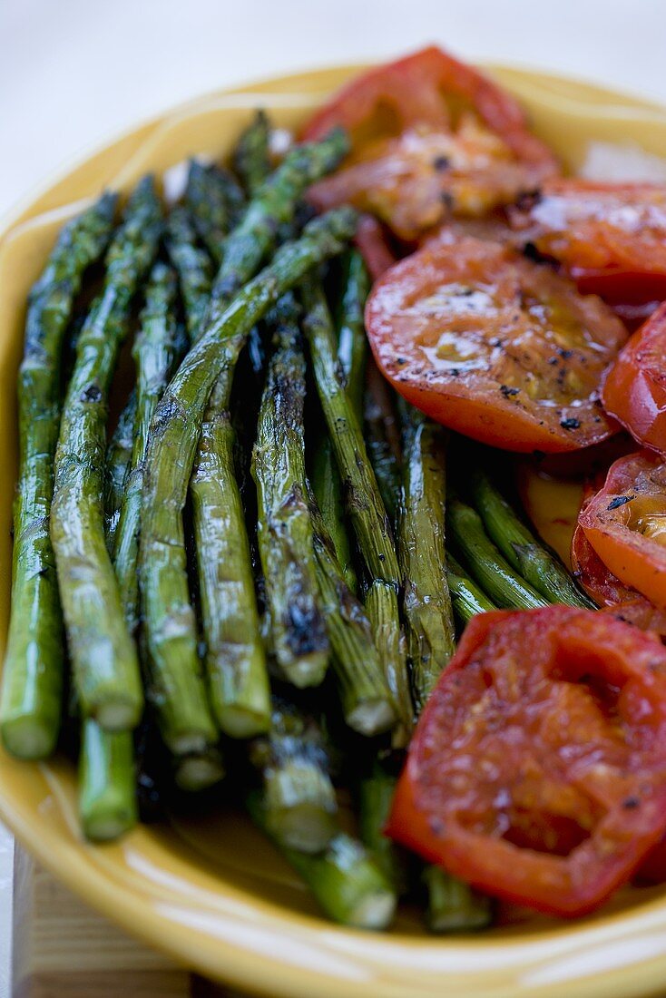 Gegrillter grüner Spargel und Grilltomaten auf einer Platte