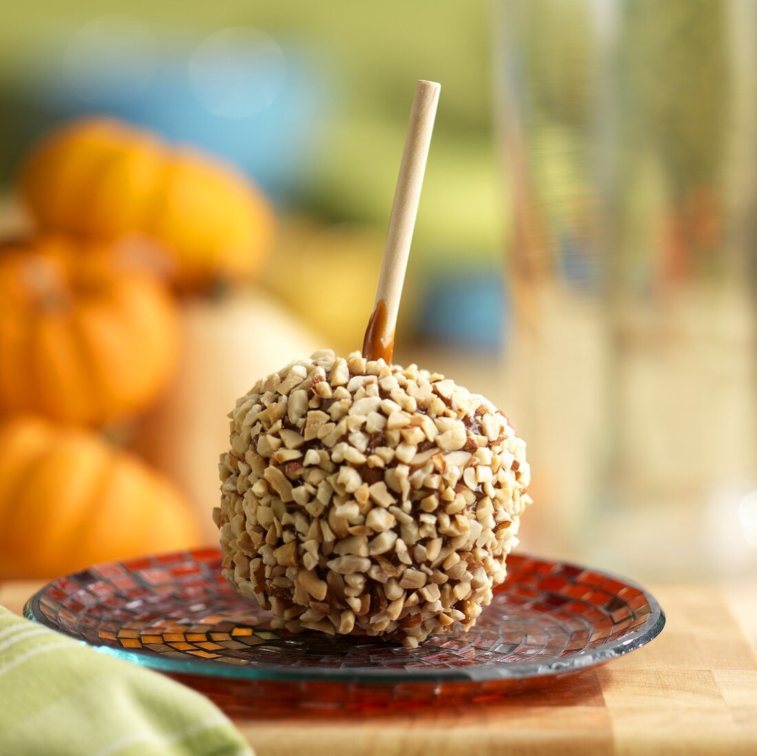 Toffee apple coated with nuts on a plate