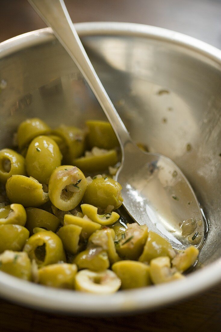 Marinierte grüne Oliven in Schüssel mit Löffel