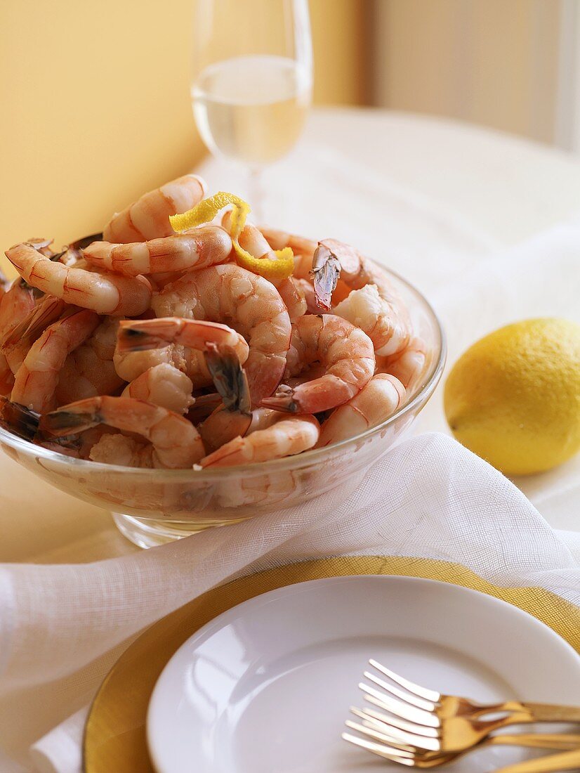 Gekochte Shrimps in Glasschüssel, Gedeck und Zitrone