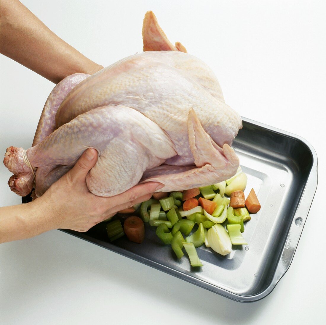 Placing Whole Chicken on a Bed of Vegetables for Roasting