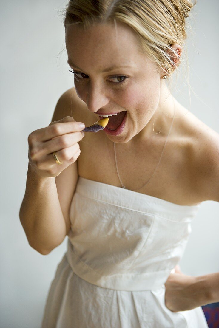 Frau in weißem Kleid isst Blue Corn Chip mit Dip