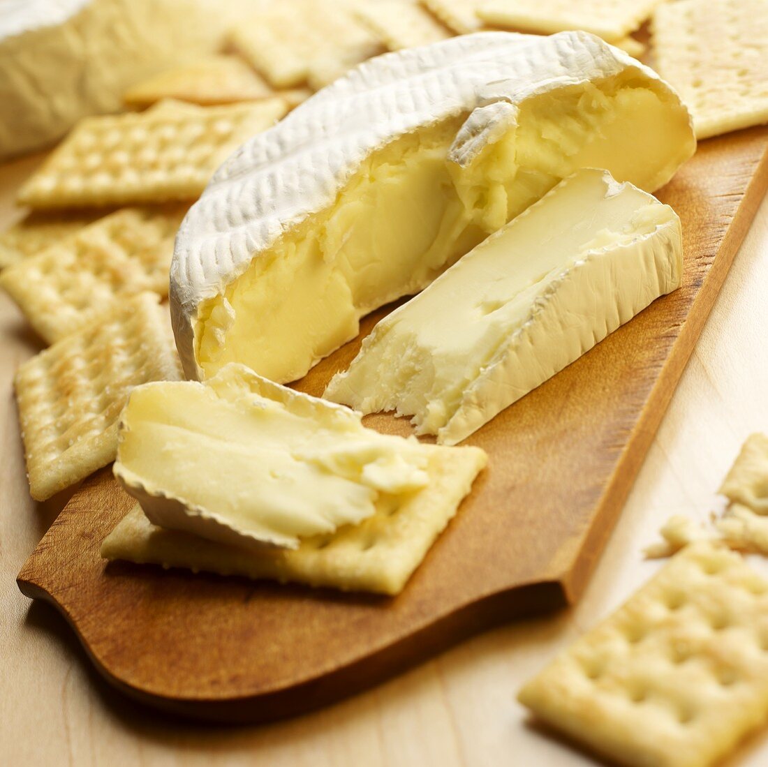 Sliced Brie Cheese with Crackers on Wooden Cheese Board