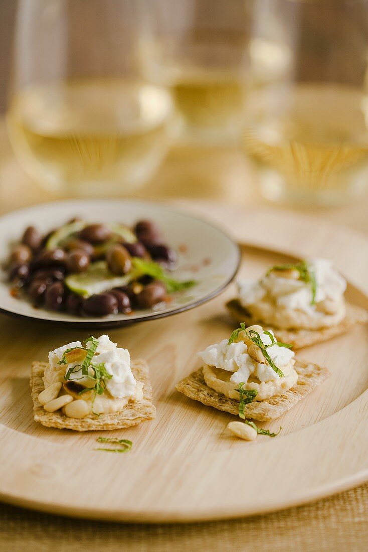 Cracker mit Hummus, Frischkäse und Pinienkernen