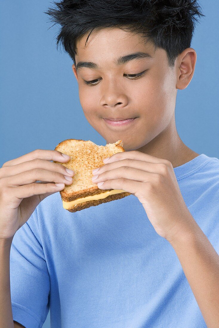 Junge hält ein getoastetes Käsesandwich in den Händen