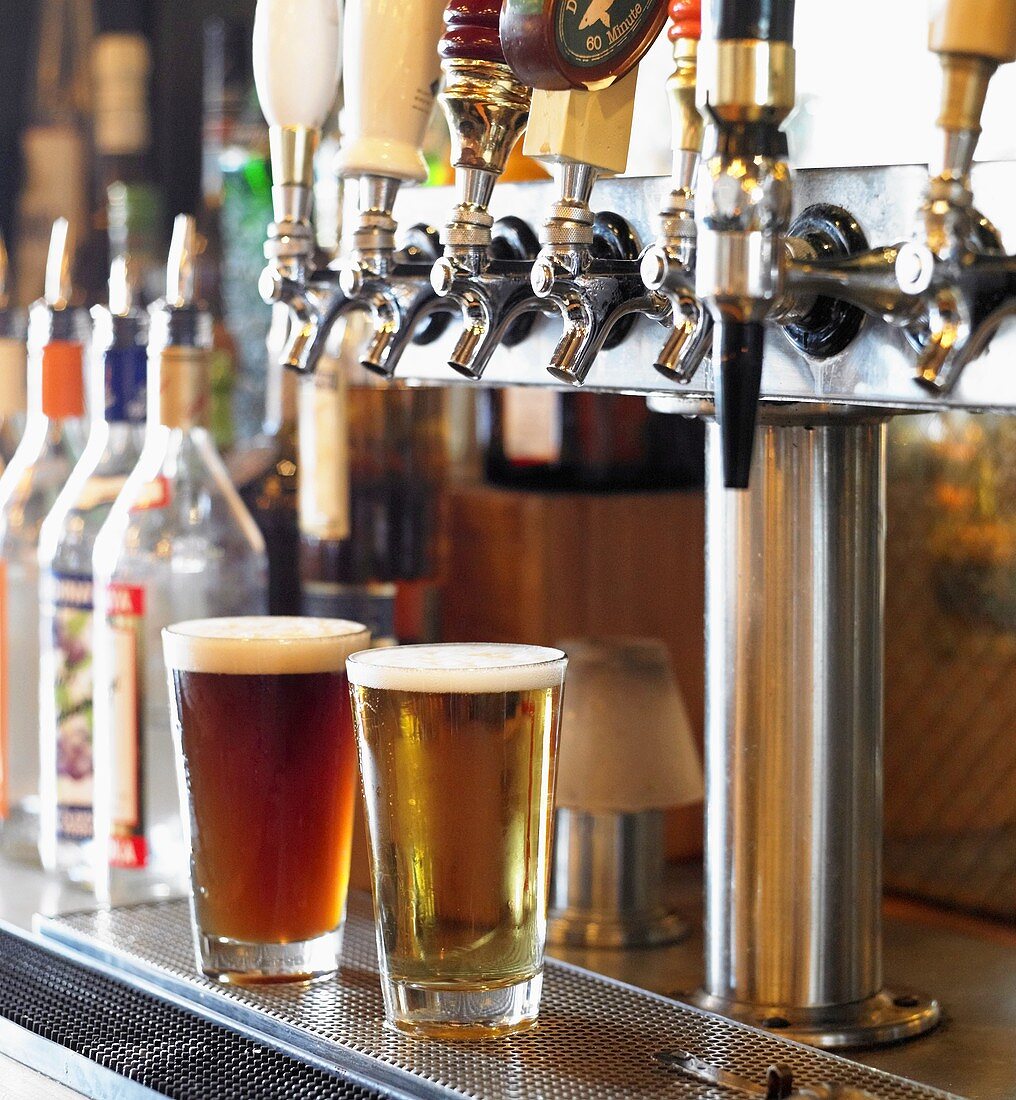 Glasses of Beer Under Taps at a Bar