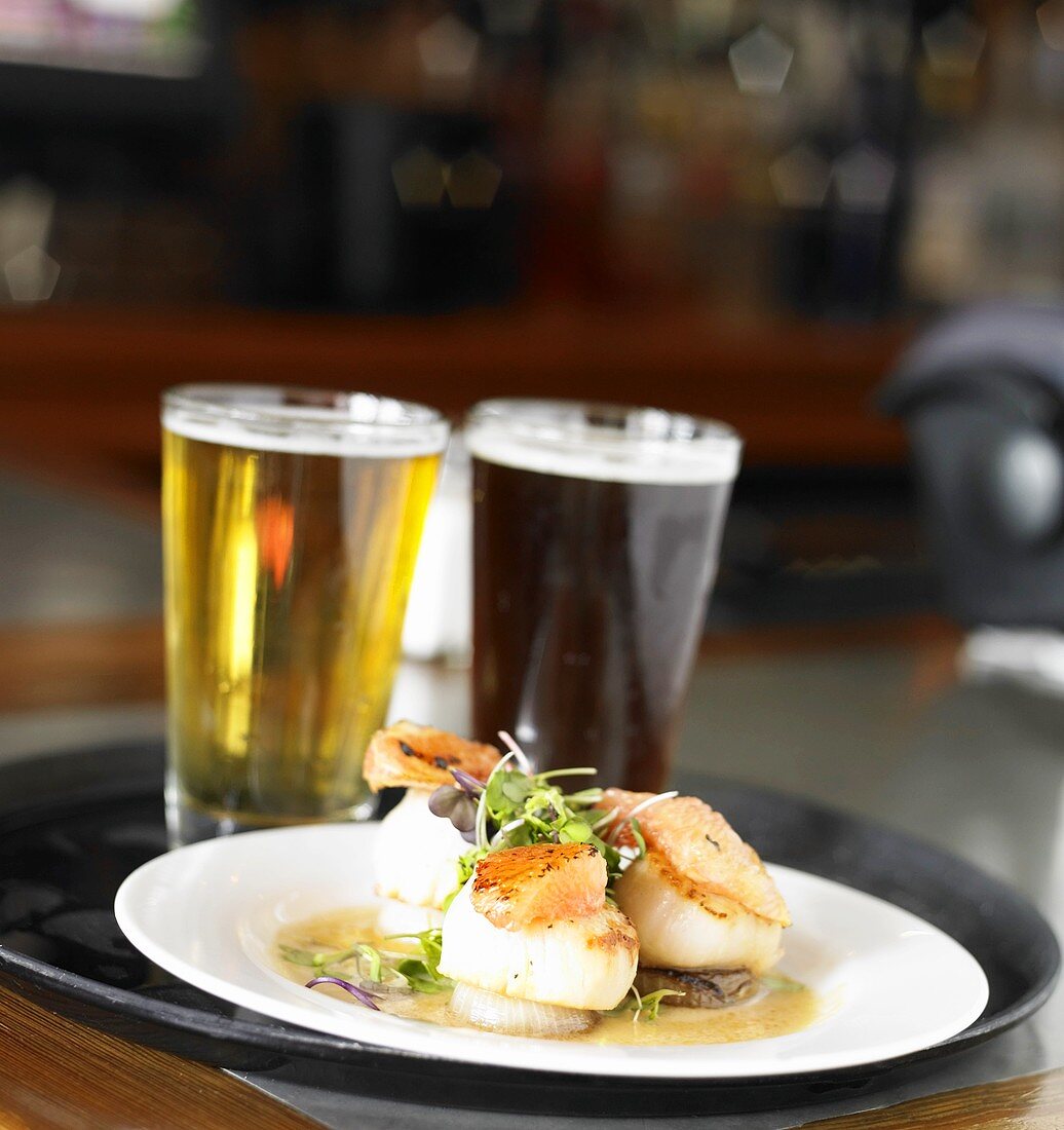 A Restaurant Tray with Seared Scallops and Dark & Light Beers