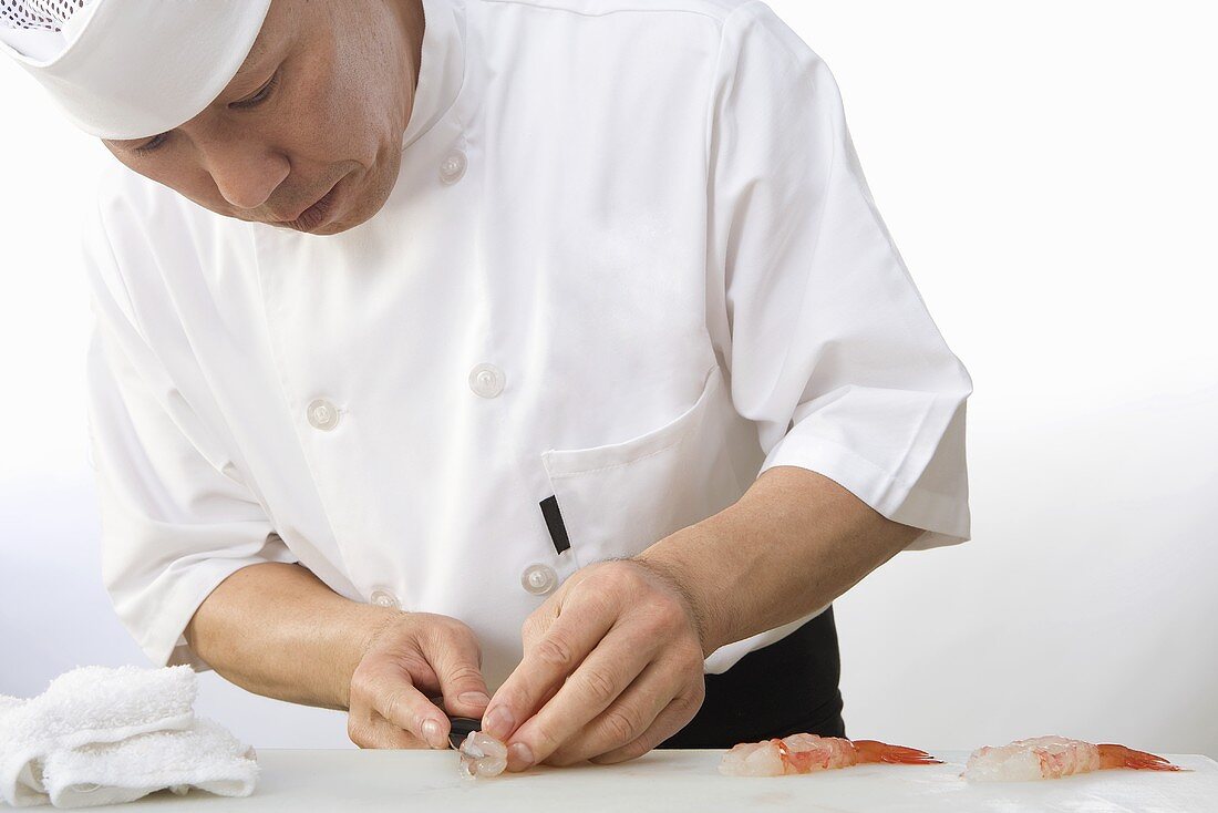 Asiatischer Koch bereitet Garnelen für Sushi zu
