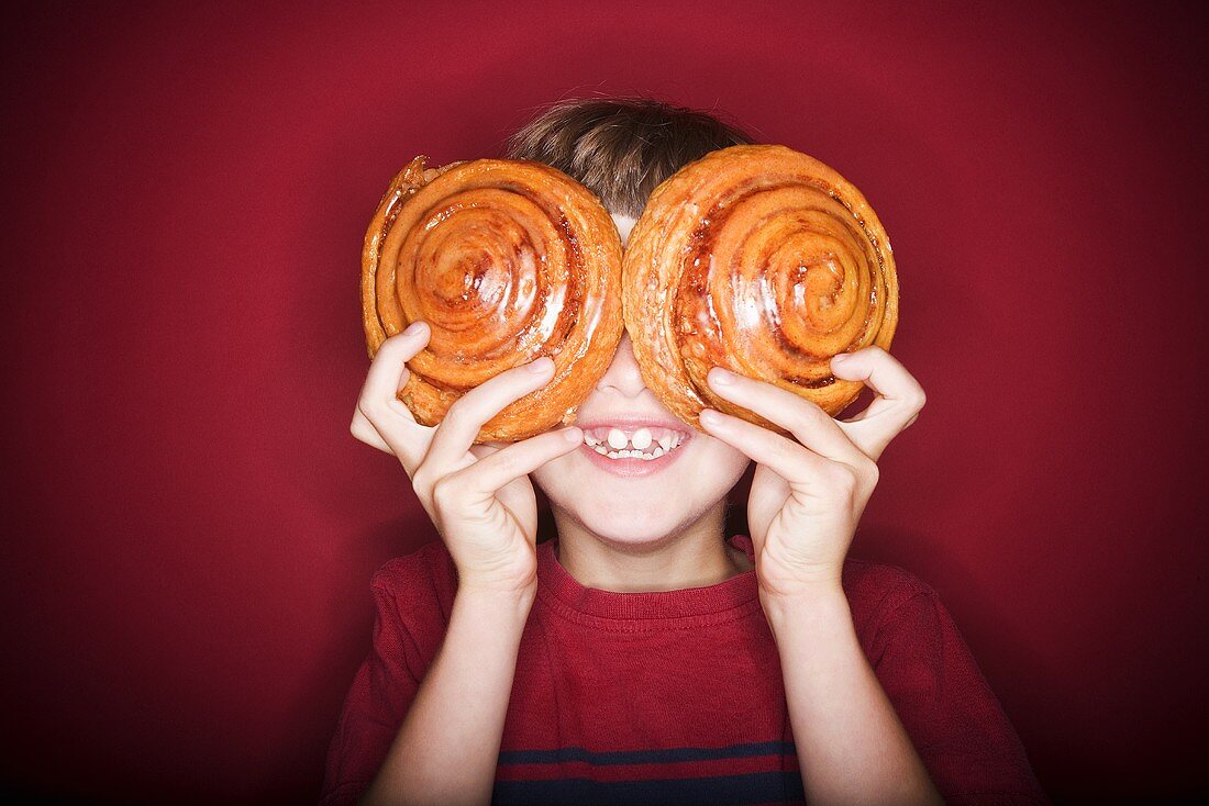 Boy Covering His Eyes with Two Large Pastries