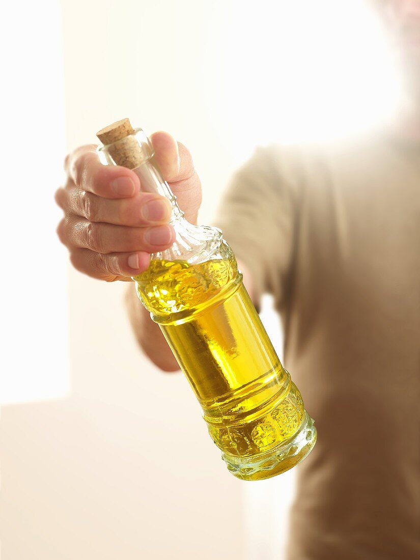 Mann hält eine Flasche Olivenöl