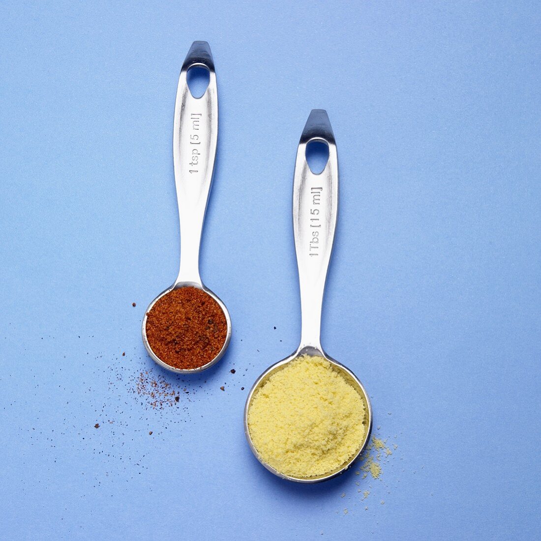 Chicken Bouillon and Chicken Seasoning in Measuring Spoons; Blue Background