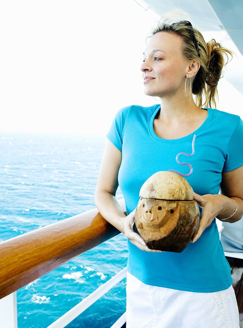 Frau mit Cocktail in der Kokosnuss auf einem Kreuzfahrtschiff