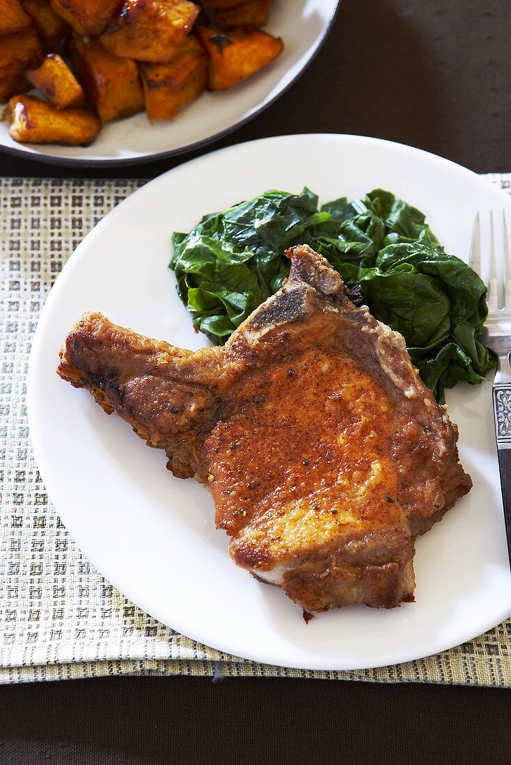 Pan Fried Pork Chop with Spinach on White Plate