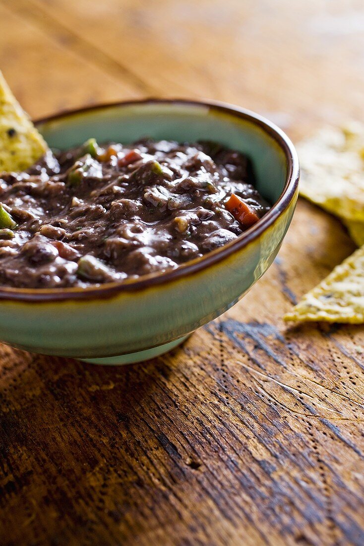Bowl of Black Bean Dip with Chips on Wood Table