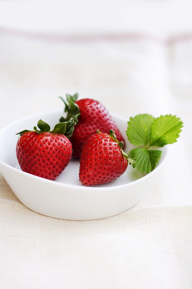 Drei Erdbeeren in einem weissen Schälchen